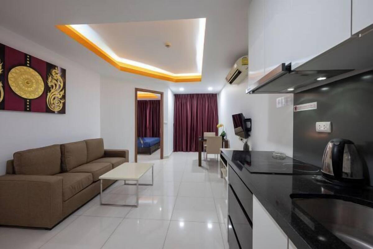 A modern kitchen with a black countertop, a built-in oven, and a coffee machine.