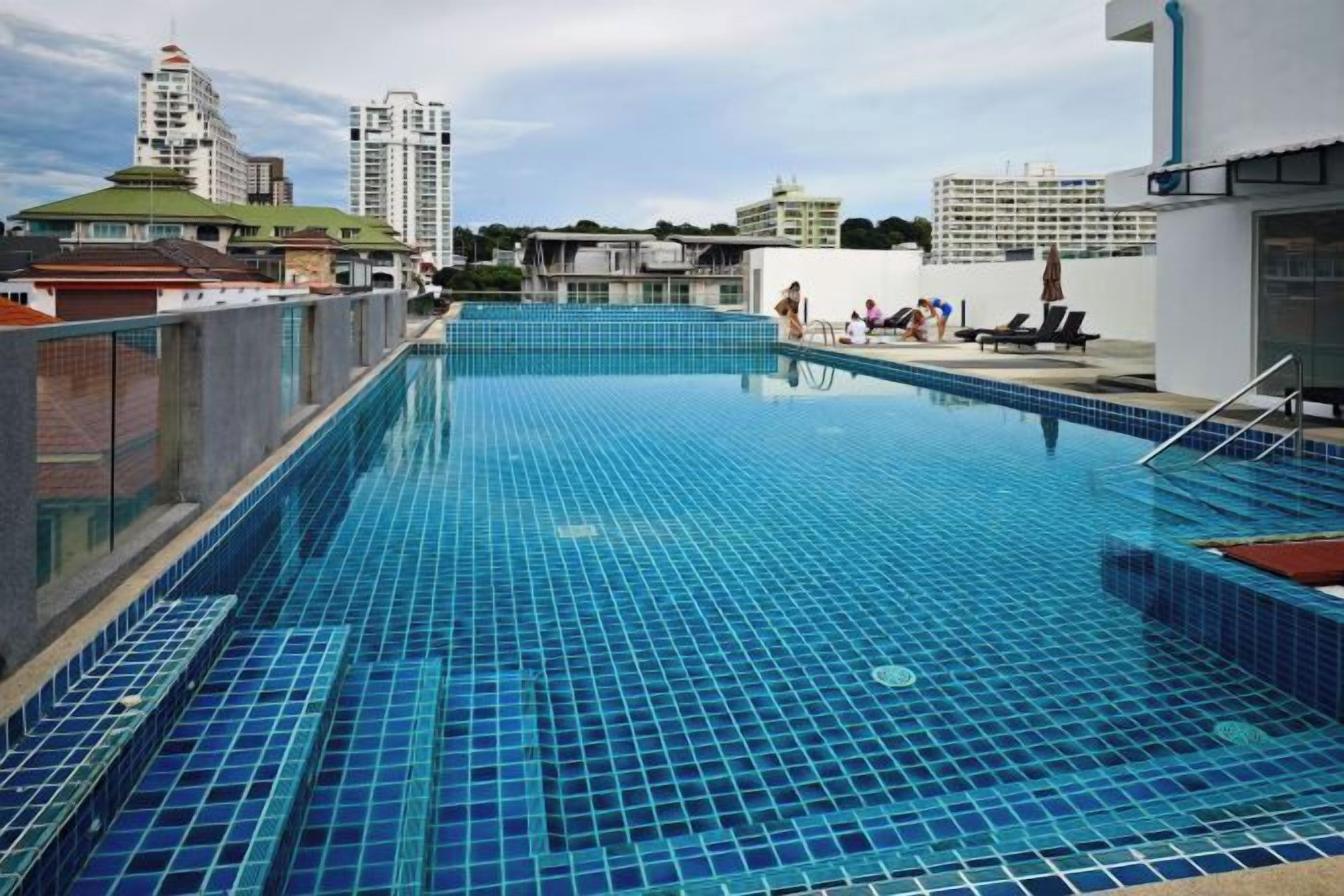 A rooftop swimming pool with a cityscape view, surrounded by buildings.