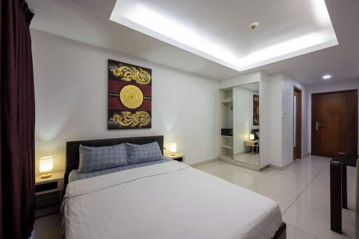 A bedroom with a bed, bedside tables, a ceiling light, a wall-mounted artwork, and a door.