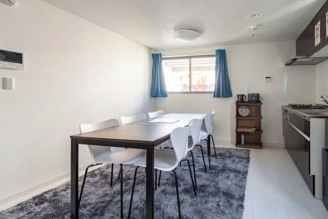 A compact kitchen with a dining area, a stove, and a clock on the wall.