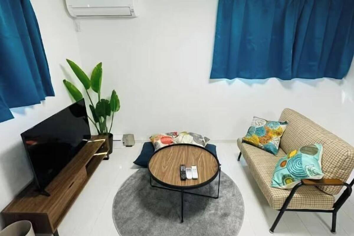 A living room with a sofa, a coffee table, a TV, and a plant.