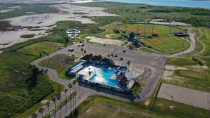 Ett flygbildsbild av ett semesterområde med en swimmingpool, tennisbanor och en baseballplan.