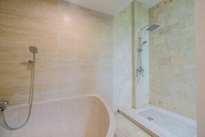Une salle de bain avec une baignoire, une douche et un petit lavabo rectangulaire.