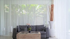 A modern living room with a grey sofa, a wooden coffee table, and a white vase with reeds. - Puri Gading Villa Jimbaran by The Lavana (Bali)
