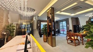 Een moderne lobby met een receptiebalie, een kroonluchter en een trap naar de bovenverdiepingen.