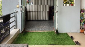 L’entrée d’un hôtel, avec un tapis de gazon artificiel vert, un mur à rayures et un panneau indiquant si des chambres sont disponibles.