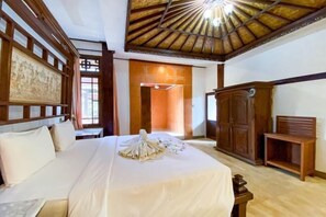 Quarto de hotel com cama, mobiliário de madeira, um armário grande de madeira e um design de teto tradicional.