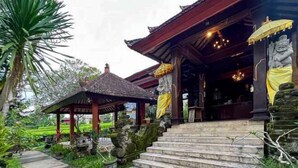 A traditional wooden structure with steps leading to a covered entrance, surrounded by greenery. - RedDoorz @ Garden Suly Villa Peliatan Ubud (Bali)