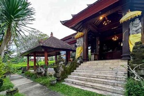 A traditional wooden structure with steps leading to a covered entrance, surrounded by greenery. - RedDoorz @ Garden Suly Villa Peliatan Ubud (Bali)