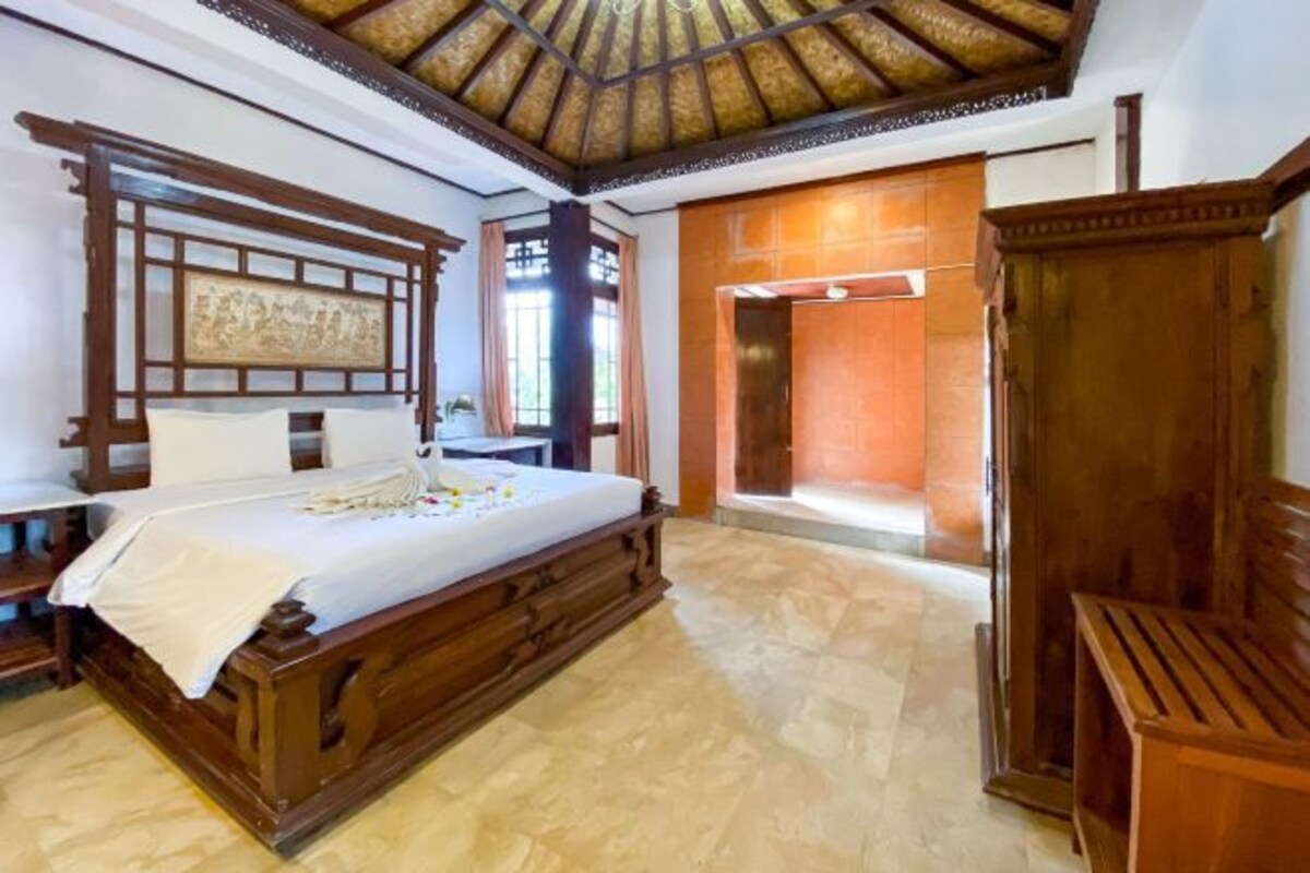 A traditional room with a wooden bed, a wooden wardrobe, and a window with a view.
