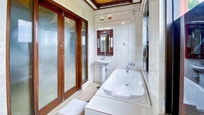 A bathroom with a bathtub, a sink, and a mirror. - RedDoorz @ Garden Suly Villa Peliatan Ubud (Bali)