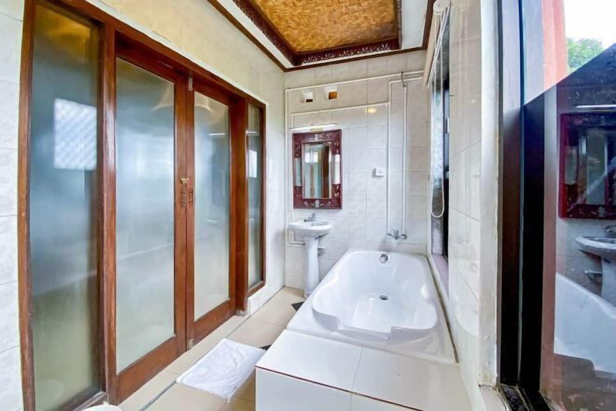 A bathroom with a bathtub, a sink, and a mirror.
