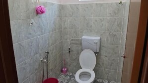 A bathroom with a toilet, shower, and a small window. - Homestay Che Naa (Kuala Kuantan)