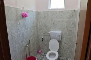 A bathroom with a toilet, shower, and a small window. - Homestay Che Naa (Kuala Kuantan)