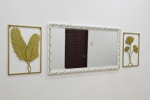 A wall with three framed items: a leaf, a door, and a flower. - Homestay Che Naa (Kuala Kuantan)
