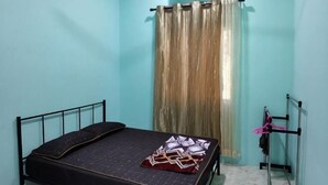 A single bed with a black headboard, a window with a curtain, and a radiator. - Homestay Che Naa (Kuala Kuantan)