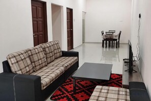 A modern living room with a sofa, coffee table, and a TV stand. - Homestay Che Naa (Kuala Kuantan)