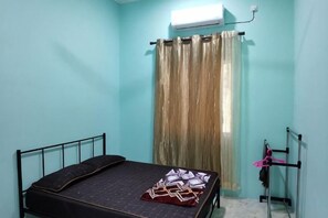 A single bed with a black metal frame, a window with a curtain, and a radiator on the wall. - Homestay Che Naa (Kuala Kuantan)