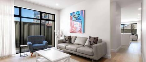 A modern living room with a sofa, armchair, coffee table, and a large window.