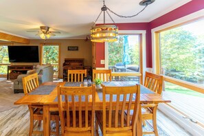 A dining area with a wooden table and chairs, a ceiling fan, and a view of the outdoors.
