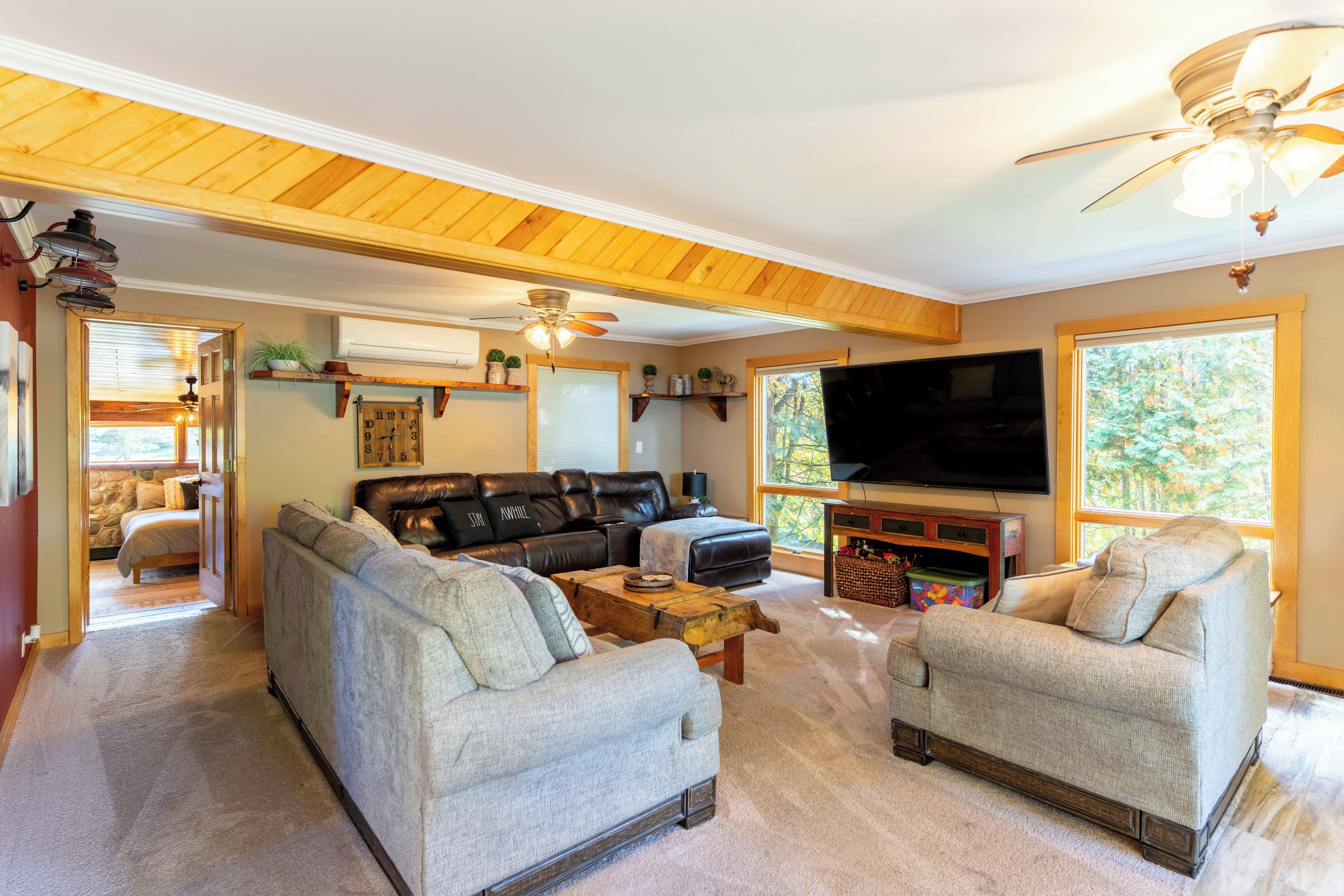 A cozy living room with a sectional sofa, two armchairs, a coffee table, and a flat-screen TV.