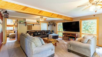 A cozy living room with a sectional sofa, two armchairs, a coffee table, and a flat-screen TV.