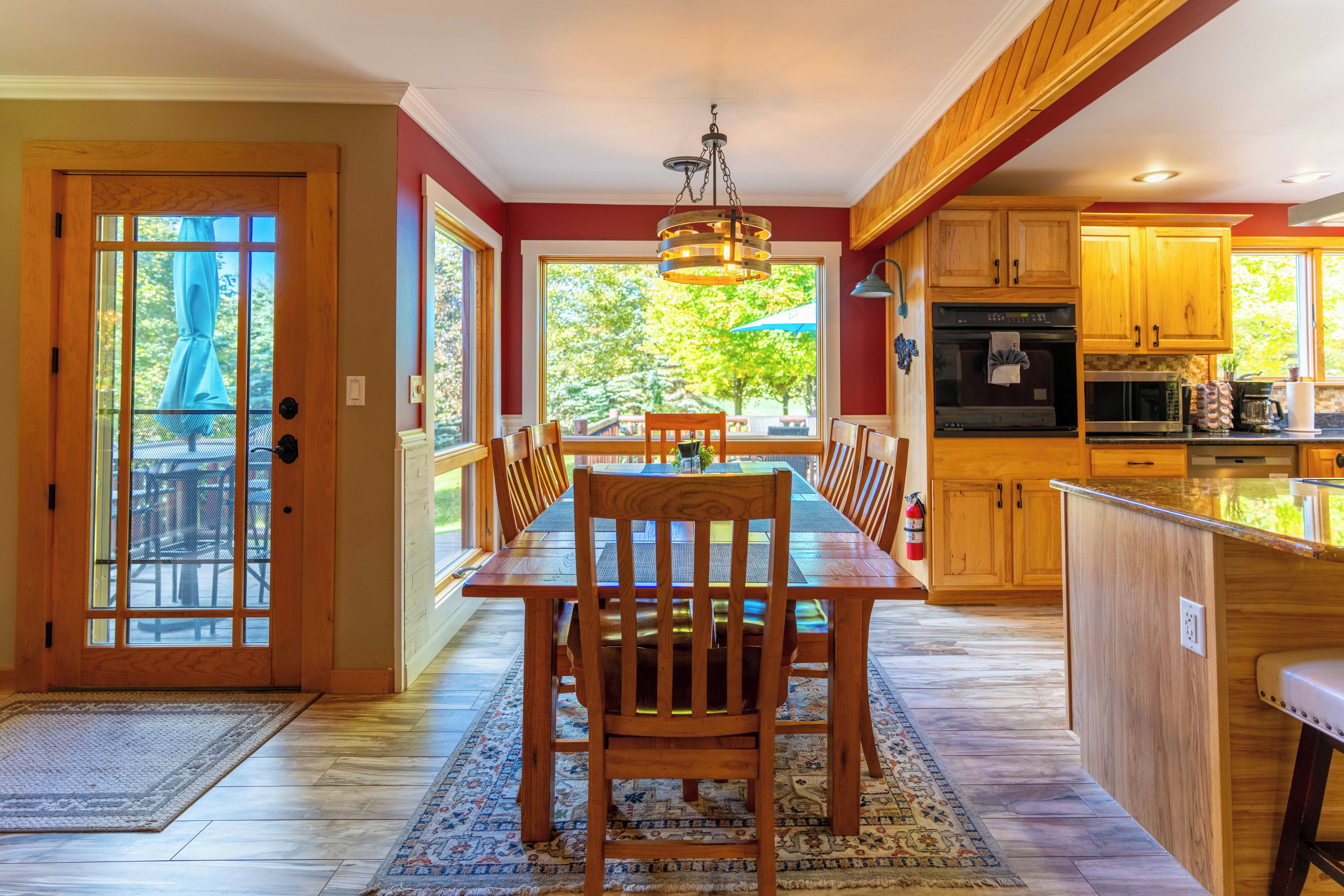 Une cuisine spacieuse avec des meubles en bois, un coin repas doté d’une grande table et de chaises, et une vue sur l’extérieur grâce aux fenêtres.