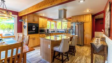 A spacious kitchen with wooden cabinets, a central island, and a dining area with chairs.