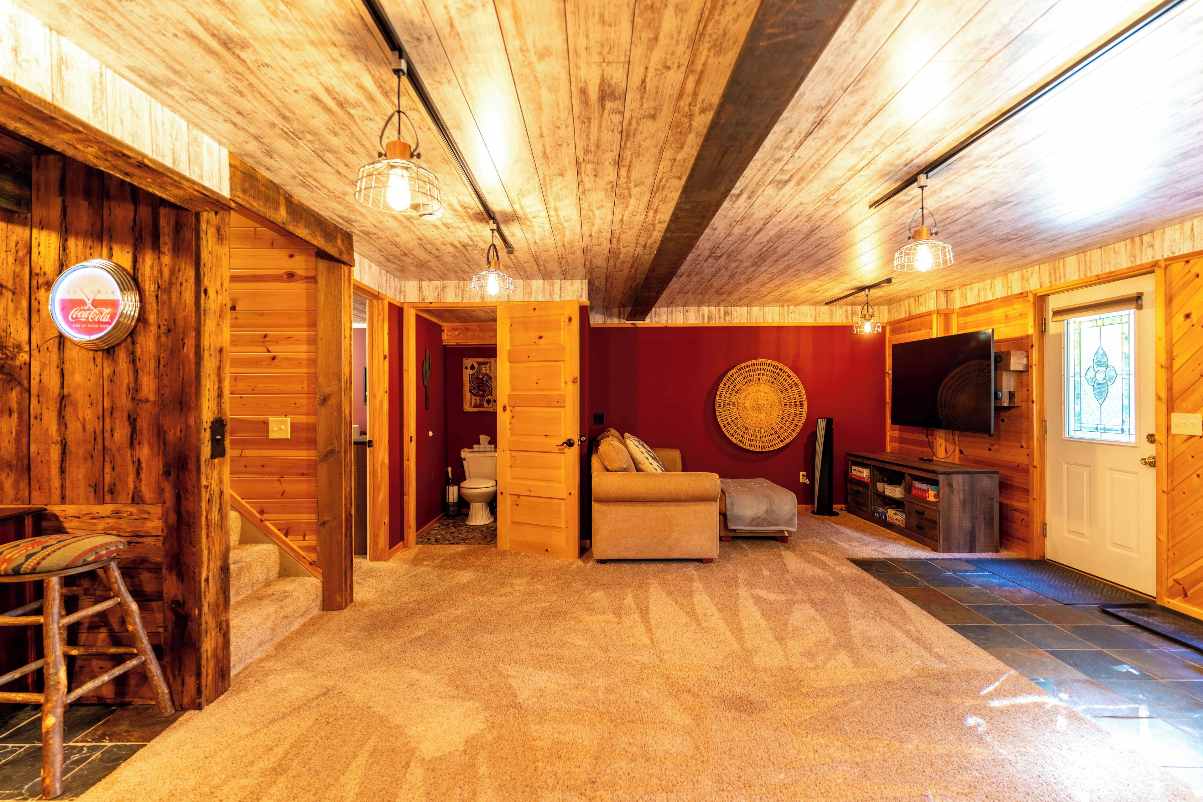 A wooden interior with a sofa, television, and a Coca-Cola branded clock.