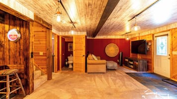 A wooden interior with a sofa, television, and a Coca-Cola branded clock.