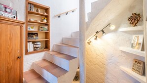 Un escalier avec une porte en bois et des étagères de chaque côté, une radio ancienne et un luminaire fixé au mur.