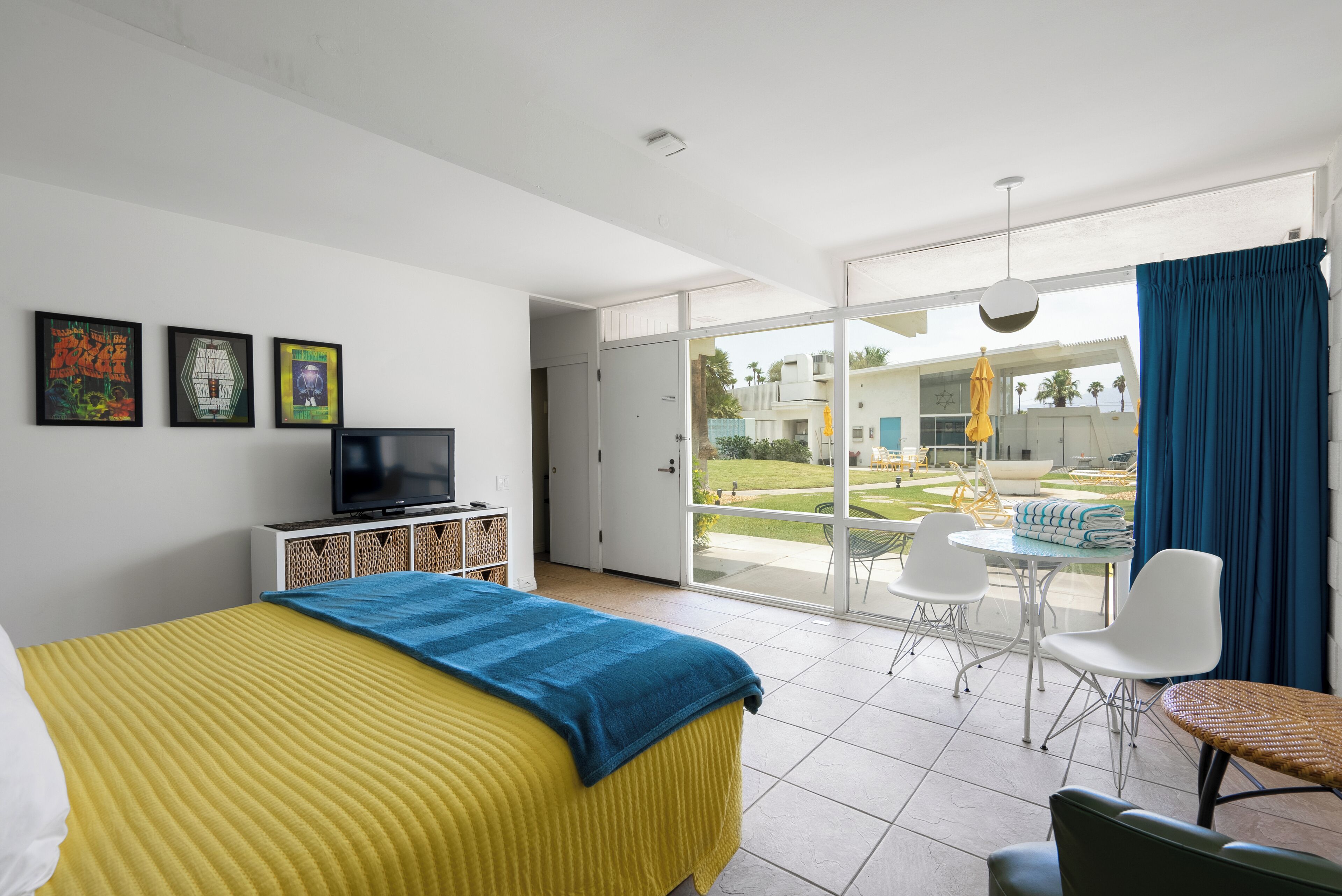 Une chambre d’hôtel avec un lit, une télévision, un balcon avec une table et des chaises, et une vue sur l’extérieur.