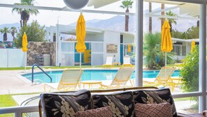 Un espace aménagé au bord de la piscine, avec des parasols jaunes, des chaises longues et une vue sur une chaîne de montagnes.