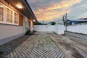 A residential property with a paved driveway, a white fence, and a house with a sloped roof. - AIRI Home,3BR near Thapae and walking str old town CNX (Chiang Mai)