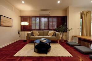 A living room with a sofa, coffee table, and a potted plant. - AIRI Home,3BR near Thapae and walking str old town CNX (Chiang Mai)