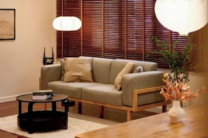 A living room with a sofa, a coffee table, and a lamp. - AIRI Home,3BR near Thapae and walking str old town CNX (Chiang Mai)