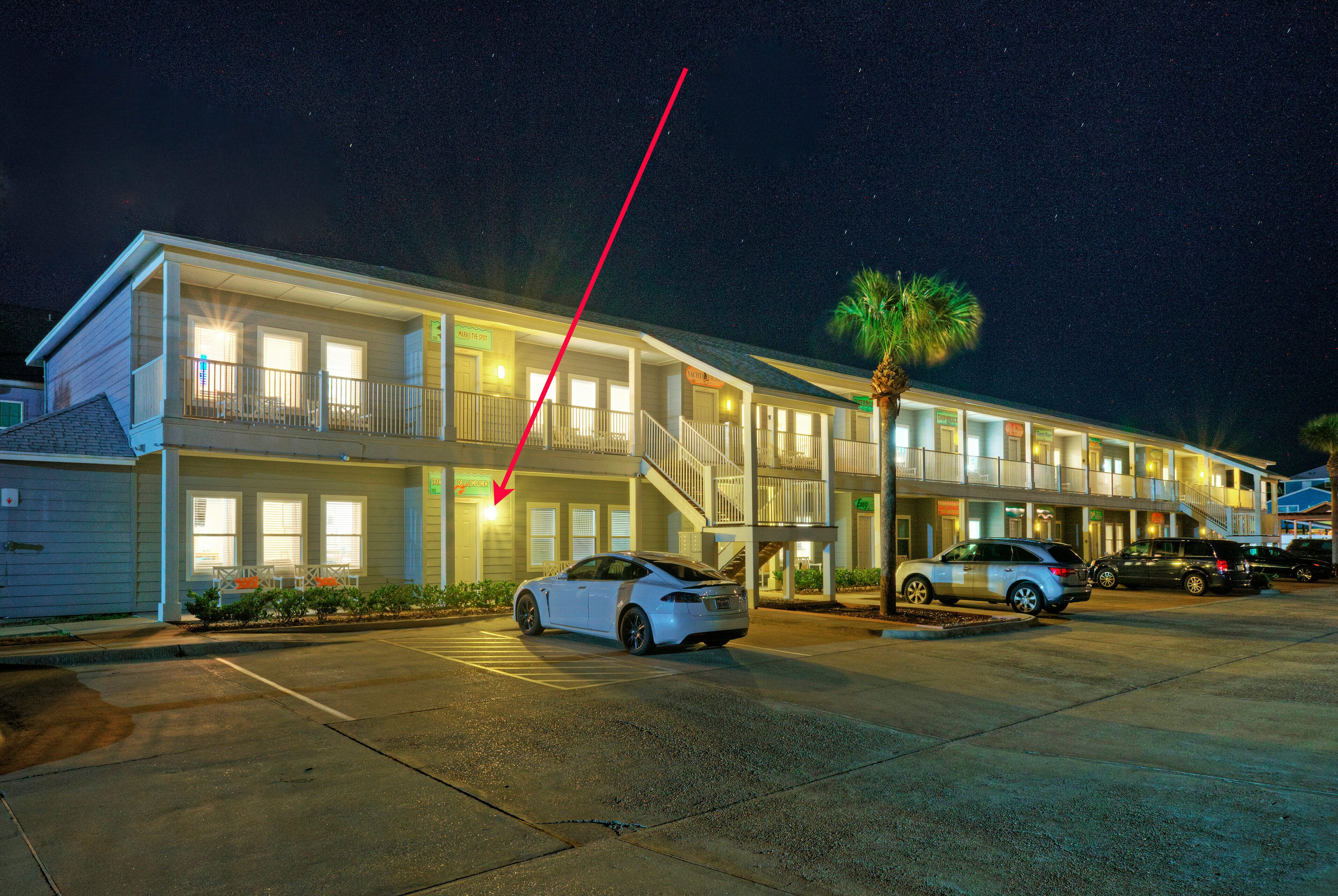 Un motel con un parcheggio, un'auto bianca parcheggiata di fronte e una freccia rossa che indica l'edificio.