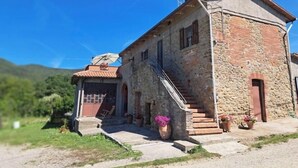 A stone building with a tiled roof, a staircase, and a small garden area with potted plants. - Marino House (Tuoro Sul Trasimeno)