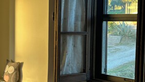 A window with a view of a garden and a pillow on the sill. - Marino House (Tuoro Sul Trasimeno)