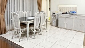 A dining area with a table and chairs, a kitchen area with cabinets, and a refrigerator. - Large Villa 3BR Cieumbuleuit near PVJ & Cihamplas (Cidadap)