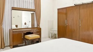A bedroom with a bed, a wooden dresser with a mirror, a small stool, and a wardrobe. - Large Villa 3BR Cieumbuleuit near PVJ & Cihamplas (Cidadap)