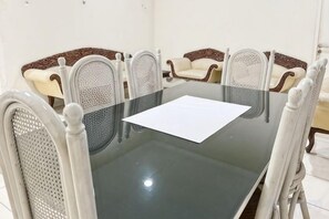 A conference room with a glass table and white upholstered chairs.