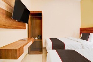 A hotel room with a bed, a wooden desk, a television mounted on the wall, and a closet. - Capital O Pusat Kota Pekanbaru Near Mall Living World Formerly Radja Homestay (Tengkerang Barat)