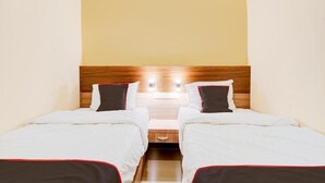 A hotel room with two single beds, a wooden headboard, and a nightstand with a lamp. - Capital O Pusat Kota Pekanbaru Near Mall Living World Formerly Radja Homestay (Tengkerang Barat)