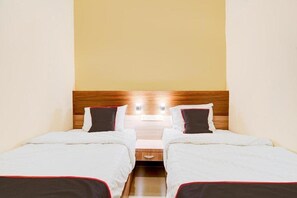 A hotel room with two single beds, a wooden headboard, and a nightstand with a lamp. - Capital O Pusat Kota Pekanbaru Near Mall Living World Formerly Radja Homestay (Tengkerang Barat)