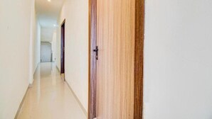 A hallway with a wooden door and a view into a room. - Capital O Pusat Kota Pekanbaru Near Mall Living World Formerly Radja Homestay (Tengkerang Barat)