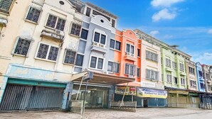 A row of colorful buildings with closed shutters, a visible storefront, and a clear sky. - Capital O Pusat Kota Pekanbaru Near Mall Living World Formerly Radja Homestay (Tengkerang Barat)