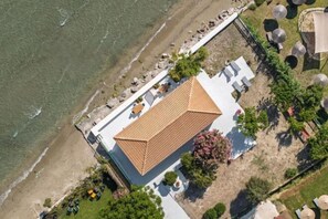 An aerial view of a coastal hotel with a tiled roof, a beachside patio, and a pool area. - Aliki's Summerhouse 1 (Argassi)