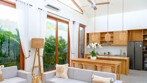 A modern living room with a sofa, coffee table, and a view of the kitchen.