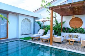 A modern outdoor pool area with lounge chairs and a wooden deck. - Villa Moon Orchid - 3 bedroom villa (Bali)